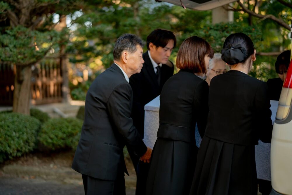 お葬式で棺桶を運ぶ遺族